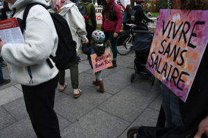 Petite enfant marchant avec l'affiche « bonbons pour tous » au premier mai à Montréal, 2026